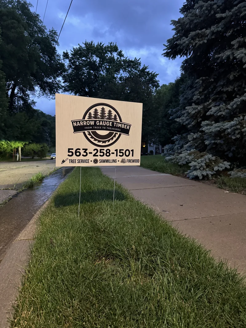 Narrow Gauge Timber yard sign advertising tree service, sawmilling, and firewood with phone number 563-258-1501