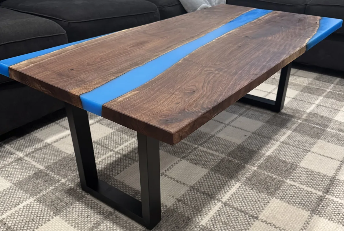 Finished live-edge walnut coffee table with a blue epoxy river pour and black steel legs